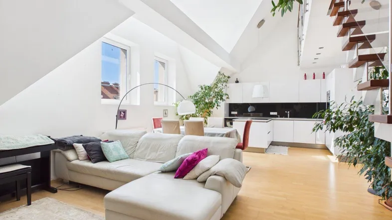 Helles, offenes Wohnzimmer mit moderner Küche, Dachschrägen und Holzboden, ideal für modernes Wohnen.