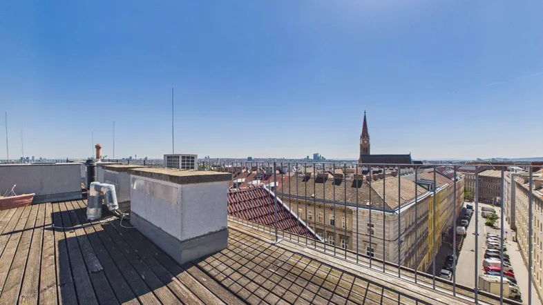 Geräumige Dachterrasse mit Holzboden und weitem Blick über die Stadt und historische Gebäude.