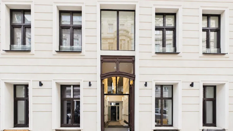 Klassische Fassade eines Wohngebäudes mit großen Fenstern und einladendem Eingangsbereich.