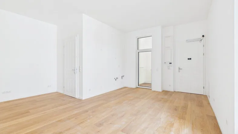 Helles, leeres Zimmer mit hellem Parkettboden und weiß gestrichenen Wänden, bereit zur Einrichtung.
