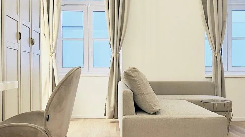 Helles Wohnzimmer mit modernem Sofa, Schrankwand und hellem Parkettboden, einladend gestaltet.