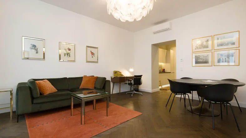 Geräumiger Wohn-Essbereich mit dunklem Fischgrätparkett, modernem Sofa und Essgruppe.
