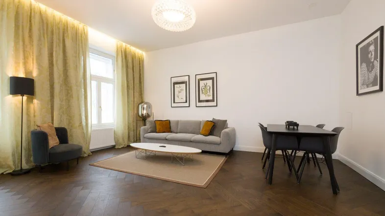 Heller Wohn- und Essbereich mit Fischgrätparkett, bequemer Couch und modernem Esstisch.