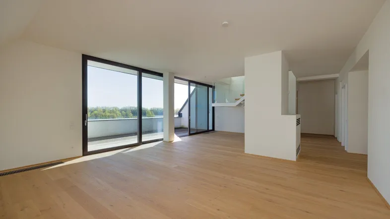 Weitläufiger Wohnbereich mit Zugang zum Balkon und viel Tageslicht durch große Fensterfronten.