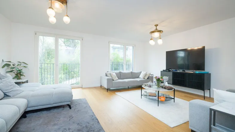 Helles Wohnzimmer mit modernem Sofa, Holzboden und Zugang zu einem französischen Balkon.