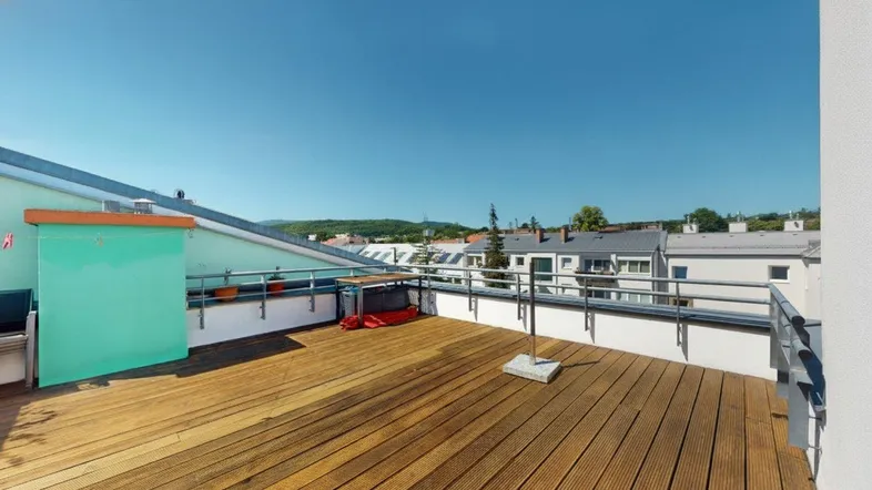 Große Dachterrasse mit Holzboden und weitem Blick über die Umgebung an einem sonnigen Tag.