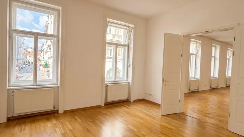 Geräumiges Zimmer mit Parkettboden und Blick auf die Stadt, verbunden mit einem weiteren Raum.
