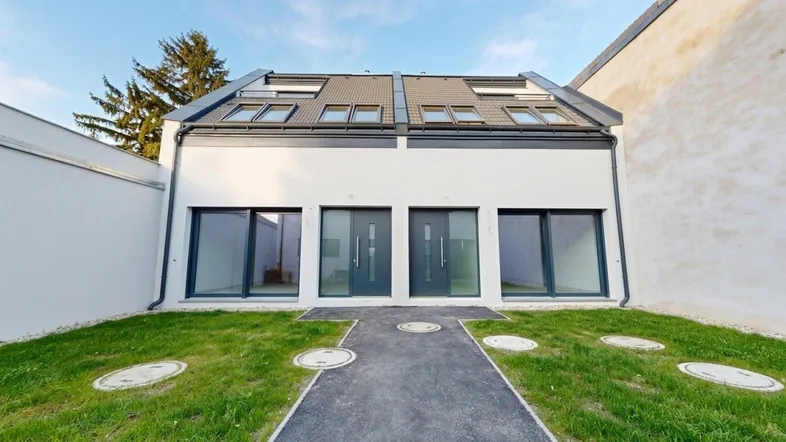 Moderne Doppelhaushälfte im Neubau mit zwei Eingängen und kleinem Vorgartenbereich.