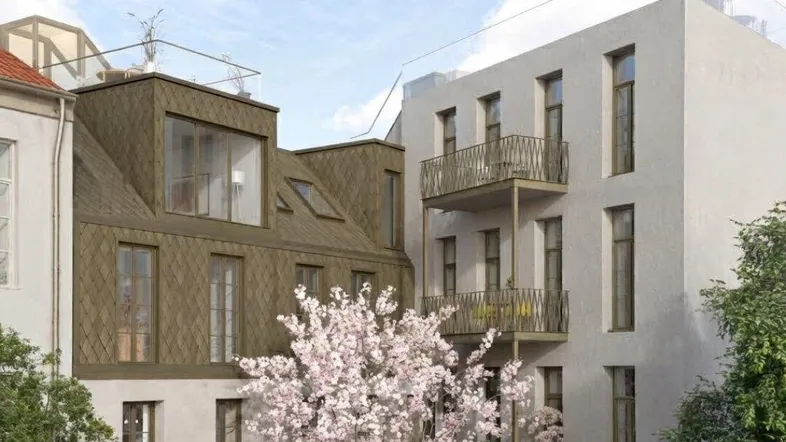 Moderne Wohngebäude mit Balkonen, einer großen Terrasse und einer Dachterrasse, umgeben von Grün.