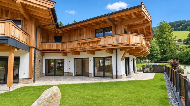 Modernes Chalet mit Holzfassade, großzügiger Terrasse und gepflegtem Garten in alpiner Umgebung.