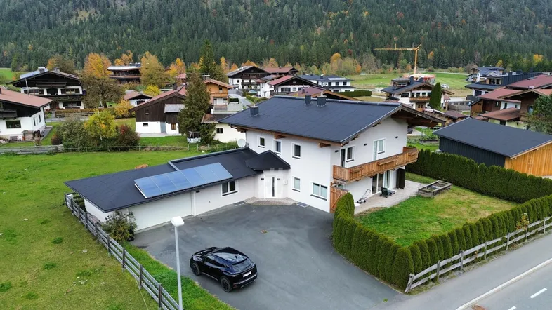 Freistehendes Haus mit Photovoltaikanlage, Garten und Bergblick in ländlicher Umgebung.
