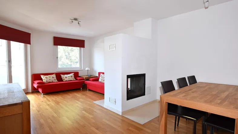 Heller Wohn- und Essbereich mit Kamin, roten Sofas und Holzboden, ideal für gemütliche Stunden.