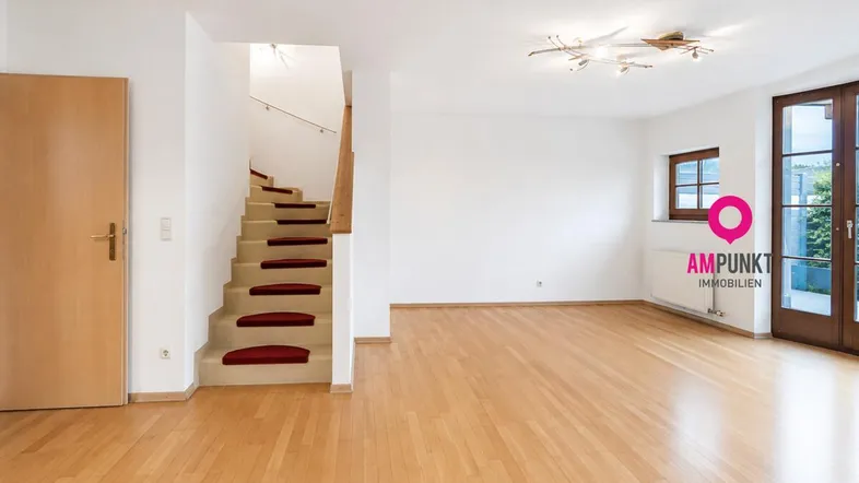 Heller, leerer Wohnbereich mit Holzparkettboden und Zugang zum Garten über große Türen.