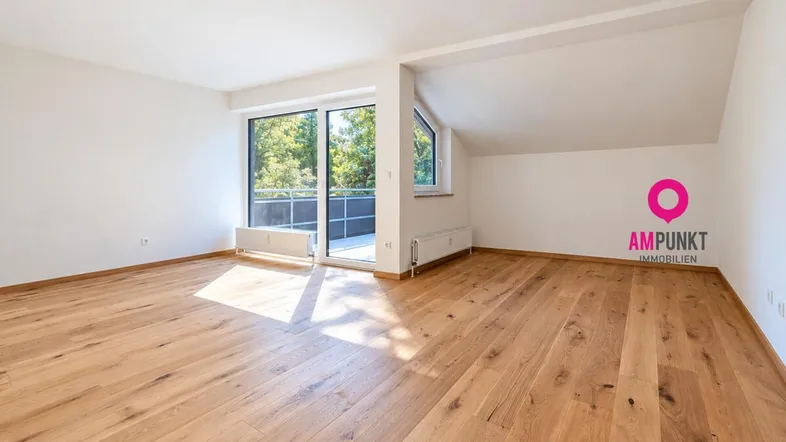 Helles Zimmer mit Holzboden, weißen Wänden, Dachschräge und Zugang zum Balkon.