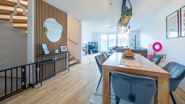 Heller offener Wohn- und Essbereich mit Holzparkettboden und moderner Holzlamellenwand.