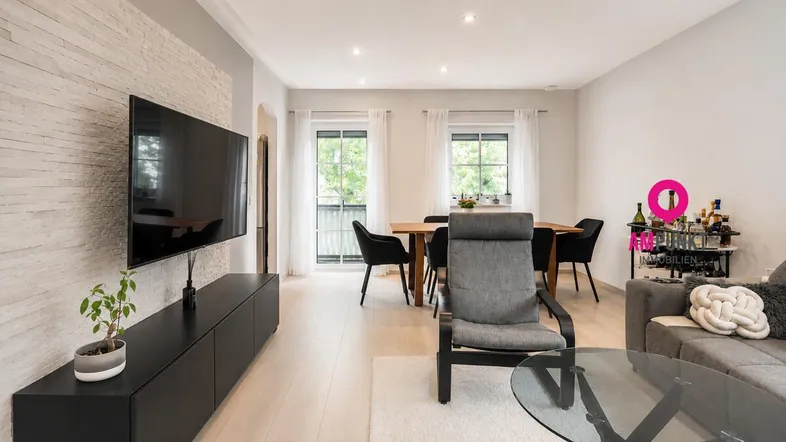 Helles Wohn- und Esszimmer mit modernem Design, Holzboden und dekorativer Steinwand.
