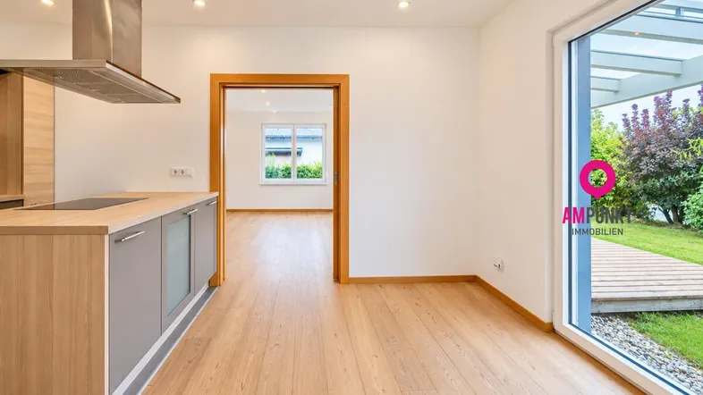 Offener Küchenbereich mit Holzboden, moderner Dunstabzugshaube und Zugang zu Terrasse und Garten.