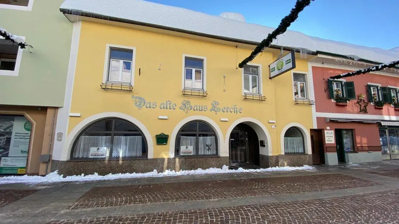 Historisches Gebäude mit gelber Fassade, Rundbogenfenstern und Schnee auf dem Dach im Winter.