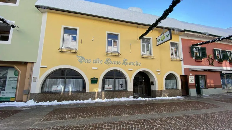 Historisches gelbes Gebäude mit Rundbogenfenstern und schneebedecktem Dach in einer winterlichen Straße.