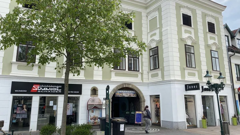 Historisches Gebäude mit Geschäften im Erdgeschoss und Wohnungen darüber, an einer belebten Straße gelegen.