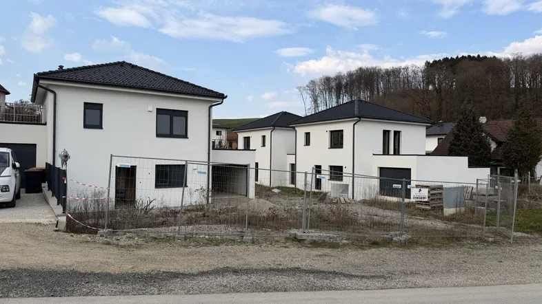 Mehrere moderne Neubauhäuser in einer Siedlung, umgeben von Baustellenbereichen.