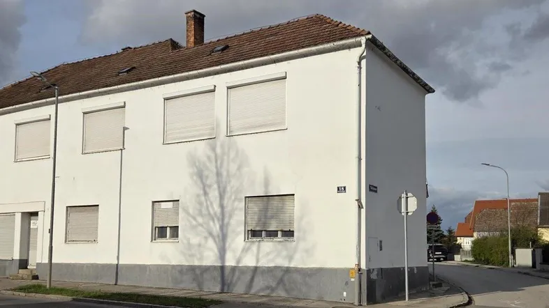 Straßenansicht des Wohnhauses mit geschlossenen Rollläden und einfacher Fassade.