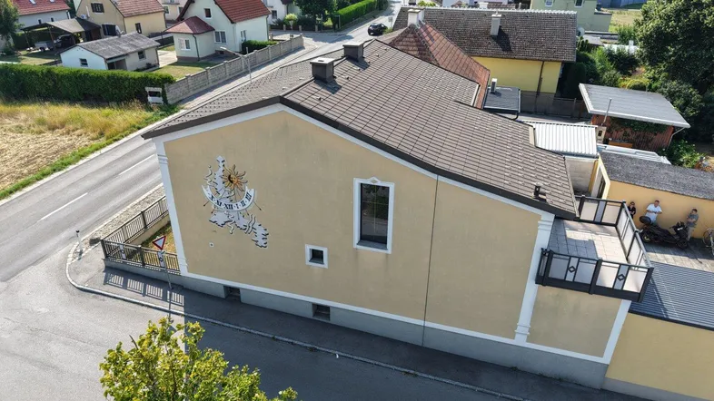 Seitenansicht des Hauses mit Sonnenuhr und Blick auf die Nachbarschaft.