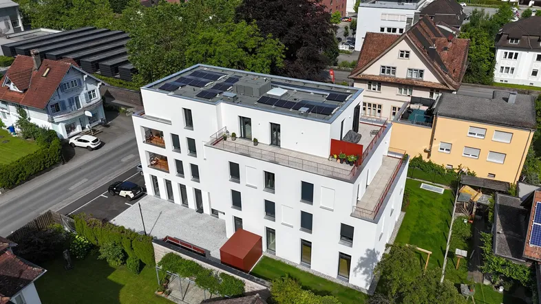 Moderne Wohnanlage mit Flachdach und Photovoltaikanlage in städtischer Umgebung.