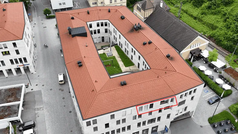 Luftaufnahme eines modernen Wohnkomplexes mit Innenhof und umliegender Stadtansicht.