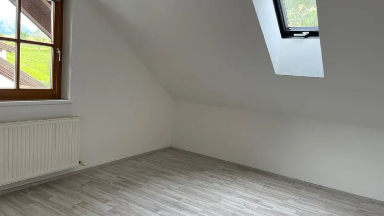Helles Zimmer im Dachgeschoss mit Laminatboden, Fenster und Dachfenster, bietet Bergblick.