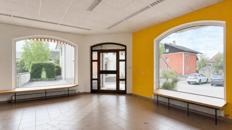 Großer offener Raum mit großen Bogenfenstern, gelben Wänden und Fliesenboden, ideal für Einzelhandel.