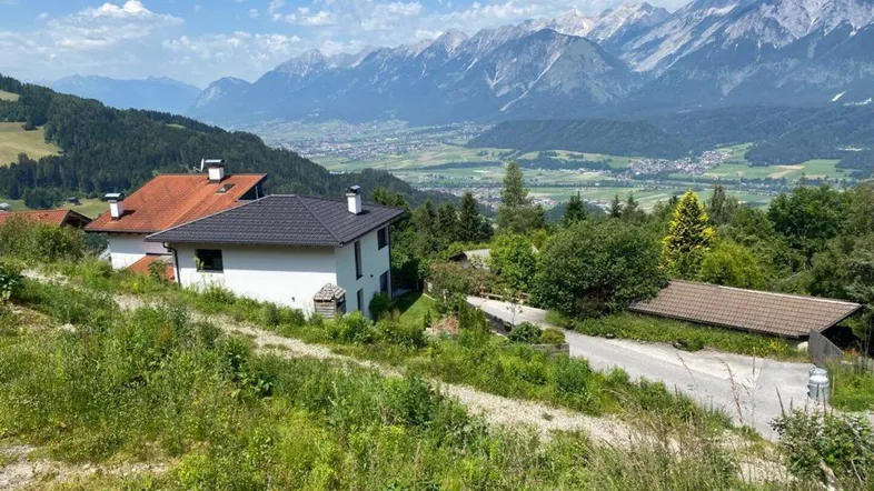Modernes Haus in Hanglage mit Panoramablick auf die umliegende Bergwelt und das Tal.