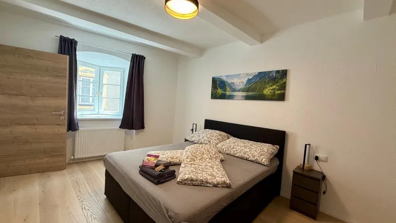 Helles Schlafzimmer mit Holzbalken an der Decke, Parkettboden und einem gemütlichen Doppelbett.