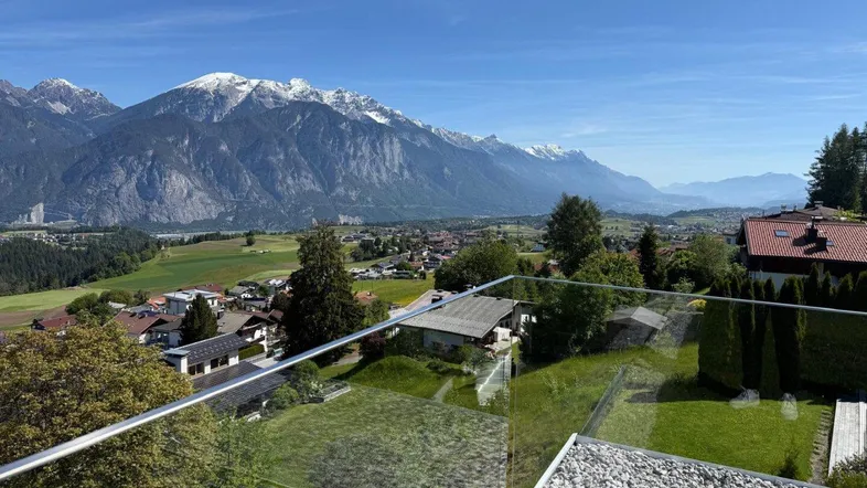 Panoramablick auf die schneebedeckten Berge und das Tal von einer modernen Terrasse.