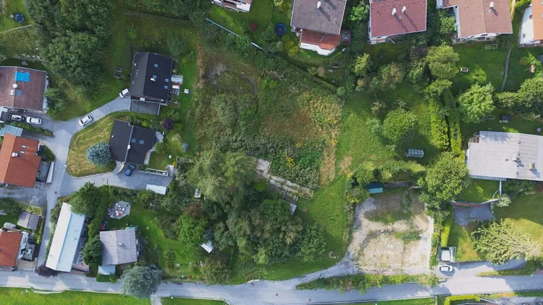 Luftaufnahme eines unbebauten Grundstücks, umgeben von Wohnhäusern und viel Grün.