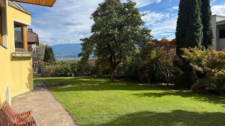 Großer Garten mit gepflegtem Rasen, altem Baumbestand und Blick auf die Landschaft.