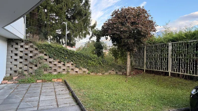 Gepflegter Gartenbereich mit Rasenfläche, gepflastertem Weg und grüner Bepflanzung, ideal zum Entspannen im Freien.