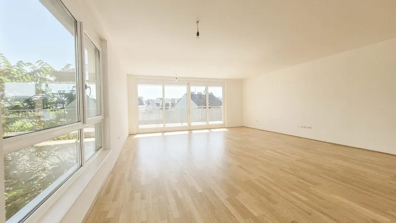 Helles, geräumiges Wohnzimmer mit Parkettboden und großen Fenstern, die viel Tageslicht hereinlassen.