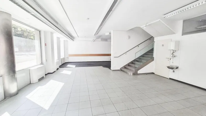 Helle, offene Fläche mit Fliesenboden, großen Fenstern und einer Treppe.