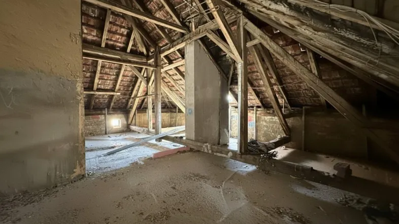 Unausgebauter Dachboden mit sichtbaren Holzbalken und Ziegeldach, bereit für den Ausbau.