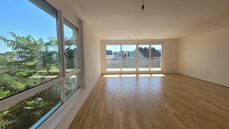 Helles, geräumiges Wohnzimmer mit Holzboden und Zugang zu einem Balkon.