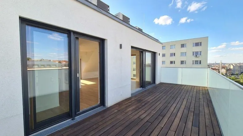 Große Dachterrasse mit Holzboden und Blick auf die Stadt, zugänglich durch Glasschiebetüren.