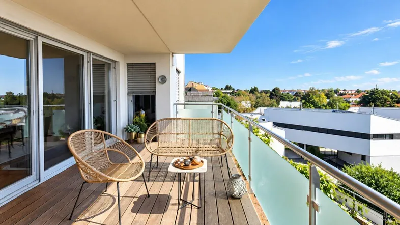 Geräumiger Balkon mit Holzboden und Rattanmöbeln, ideal für entspannte Stunden im Freien.