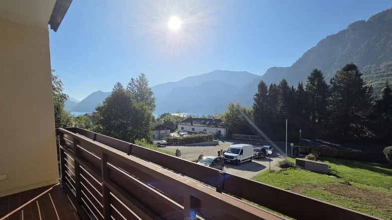 Sonniger Balkon mit atemberaubendem Blick auf den See und die umliegenden Berge.