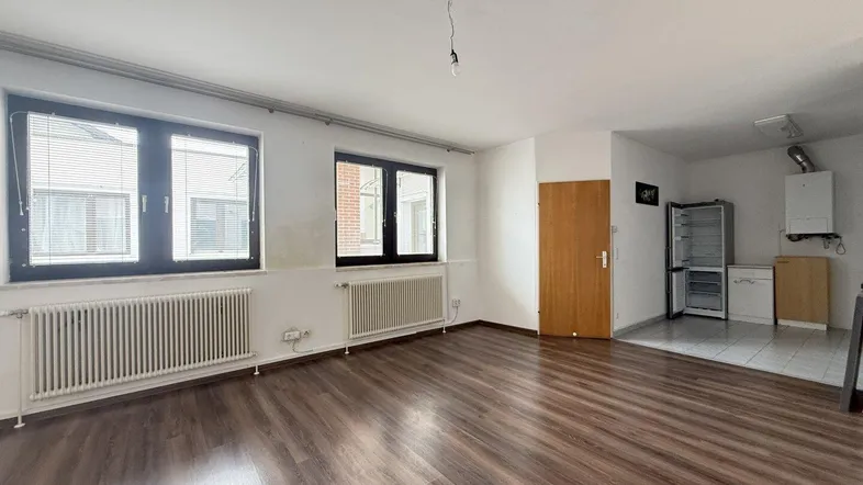 Heller Wohnraum mit Laminatboden, zwei Fenstern und Heizkörpern, bietet viel Tageslicht und Ausblick.