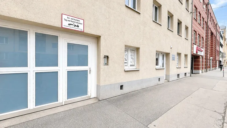 Fassade eines Geschäftsgebäudes mit Eingangsbereich und Fenstern, die auf eine belebte Straße blicken.