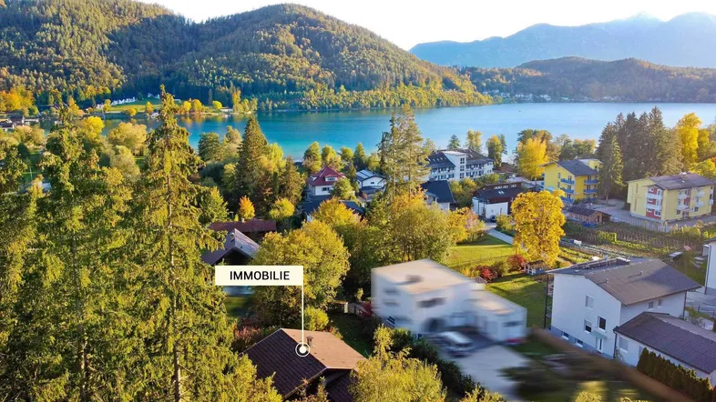 Panoramablick auf die Immobilie am Seeufer mit umliegenden Bergen und üppiger Vegetation.