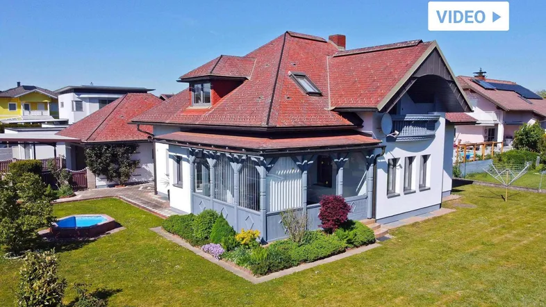 Gepflegtes Einfamilienhaus mit rotem Ziegeldach, großem Garten, kleinem Pool und überdachter Veranda.