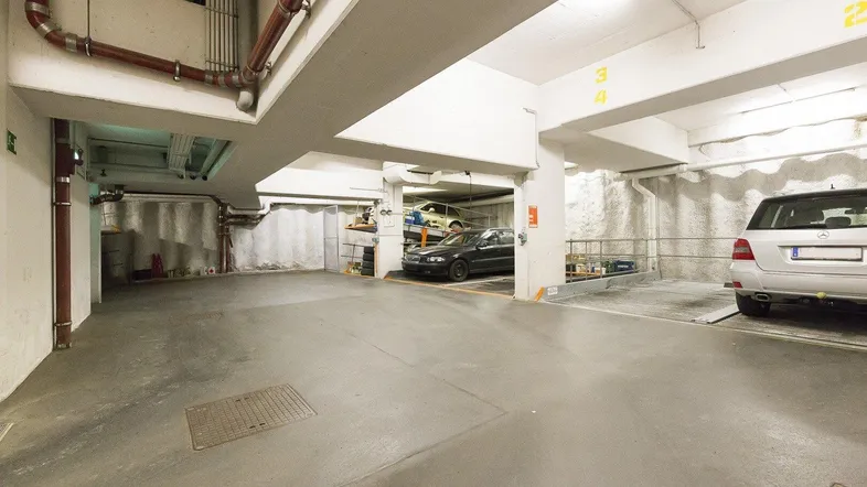 Geräumige Tiefgarage mit Betonboden und mehreren Parkplätzen, inklusive Duplex-Parksystem.