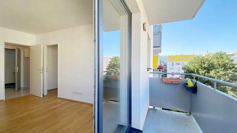 Helles Zimmer mit Parkettboden und direktem Zugang zu einem sonnigen Balkon.